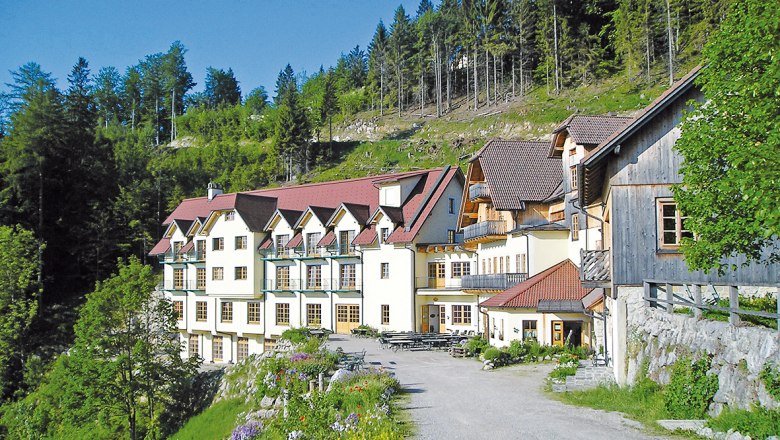 Ein gro&szlig;es Geb&auml;ude mit roten D&auml;chern in einer gr&uuml;nen, bewaldeten Umgebung.