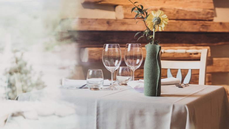 Eleganter Restauranttisch mit Gl&auml;sern und Blume in Vase.