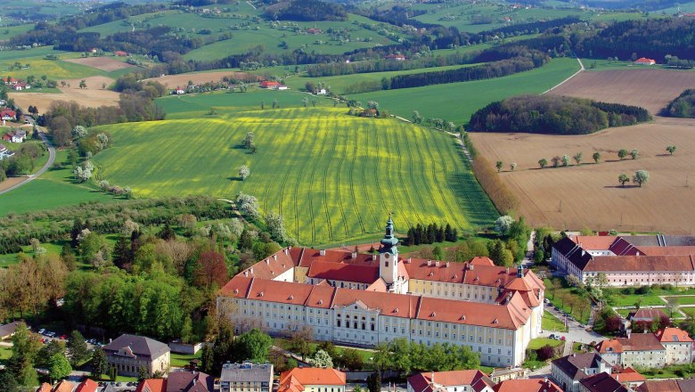 Luftaufnahme des Benediktinerstifts Seitenstetten umgeben von gr&uuml;nen Feldern und H&uuml;geln.