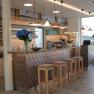 Moderne Bar mit Holzdekor, Barhockern und Blumen.