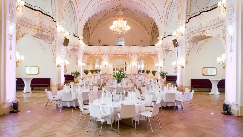 Eleganter Saal mit gedeckten Tischen und Kronleuchter.
