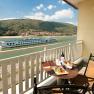 Balkon mit Tisch, Wein und Snacks, Blick auf Fluss und vorbeifahrendes Schiff.