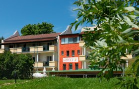 Außenansicht des Hotel-Restaurants Liebnitzmühle mit grünem Rasen und Bäumen im Vordergrund.