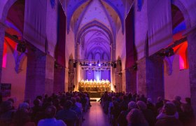Innenansicht der Minoritenkirche in Krems während eines Konzerts mit beleuchtetem Chor.