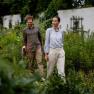 Ein Mann und eine Frau spazieren durch einen gr&uuml;nen Garten, umgeben von Pflanzen.