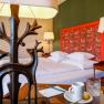 Ein stilvoll eingerichtetes Hotelzimmer mit einem Bett, dekorativen Lampen und einem Tisch mit Tasse und Glas.