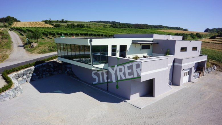 Modernes Weingut Steyrer mit Glasfassade und umliegenden Weinbergen.