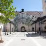 Innenhof mit Glasdach und B&auml;umen, umgeben von Geb&auml;uden.