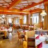 Gem&uuml;tliches Restaurant mit Holzm&ouml;beln und gedeckten Tischen.
