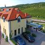 Au&szlig;enansicht des Hotel Turmhof mit roten D&auml;chern und umliegenden Weinbergen.