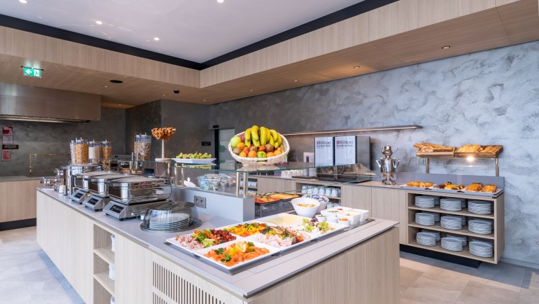 Ein reichhaltiges Fr&uuml;hst&uuml;cksbuffet mit Obst, Geb&auml;ck, Aufschnitt und Cerealien in einem modernen Hotelrestaurant.
